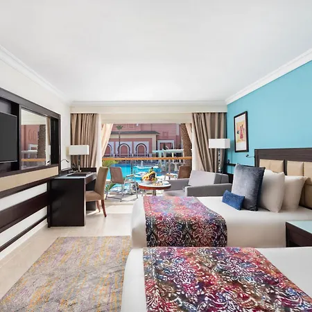 Savoy Le Grand Hotel Marrakech Marrakesh Buitenkant foto The photo shows a stylish hotel room featuring two beds, each adorned with colorful patterned bedspreads. The walls are painted in a calming blue hue, and there are large windows allowing natural light to fill the space, with a view of an outdoor poo